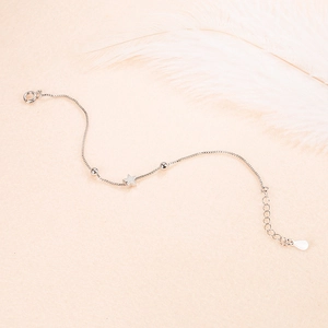 Minimalist silver star charm bracelet with metallic beads on soft pink background