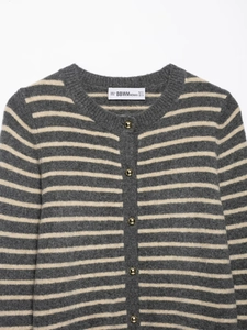 Close-up of grey and cream striped knit cardigan with textured gold dome buttons