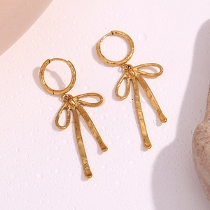 Dettaglio macro di orecchini a fiocco placcati oro con texture in metallo martellato