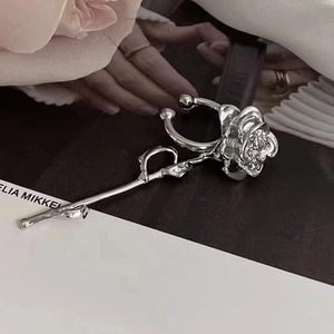 Detailed view of a silver rose flower earring set against a lifestyle magazine background
