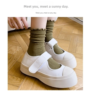 Close-up of green ruffle socks with Mary Jane canvas shoes on wooden floor