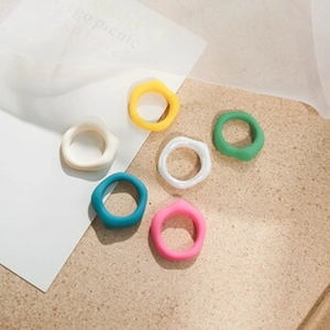 Various colorful irregular resin rings in yellow, green and pink on a textured background