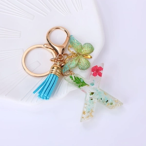 Detail of floral resin letter X keychain with green leaves and light blue tassel