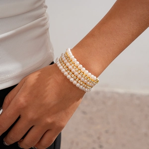 Detail of multilayer gold bracelet set with white pearls and sparkling clear rhinestones