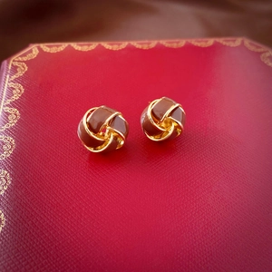 Detailed macro view of gold-plated twisted ball earrings on a luxury red velvet gift box