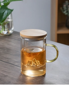 Detail of a glass tea cup with a wooden lid and mountain-shaped base showing flower tea