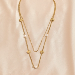 Double-layer gold heart necklace with pearls on satin background for women