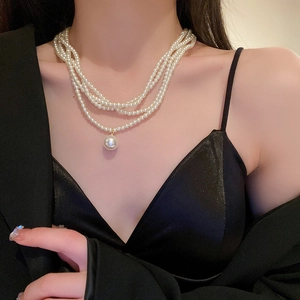 Close-up of layered baroque pearl necklace featuring a large round pearl pendant on a model