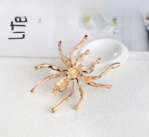 Detail of a golden spider brooch with black enamel accents and a secure safety pin back