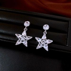 Detailed view of silver star earrings with sparkling rhinestones on black display