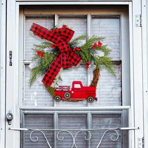 Weihnachtskranz mit rotem Oldtimer-Truck, Tannenzweigen und karierter Schleife an weißer Tür