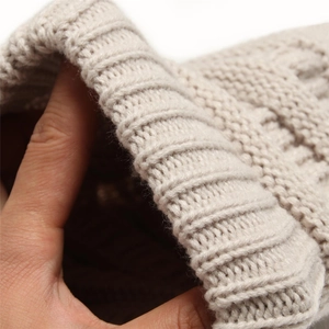 Detail of beige knit beanie showing the ribbed edge texture and thick yarn quality