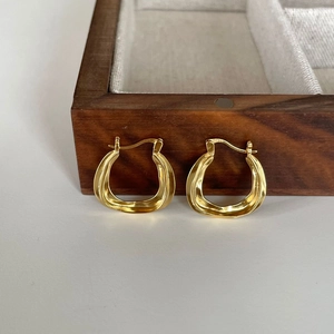 Irregular wavy gold earrings in 925 sterling silver on a dark wooden jewelry box