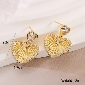 Detailed view of 18K gold heart earrings with zircon stones on white display steps