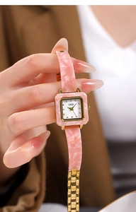 Nahaufnahme einer luxuriösen quadratischen Quarzuhr mit rosa Marmorierung und Goldarmband