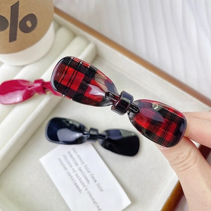 Close-up of a red and black checkered ribbon hair clip held to show acetate texture