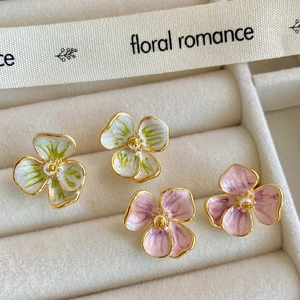 Vue macro d'élégantes boucles d'oreilles en émail floral violet et vert sur velours