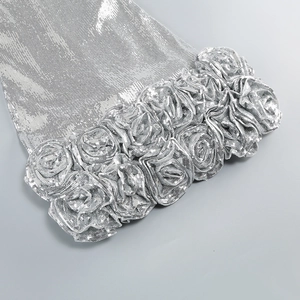 Detailed view of silver sequin fabric featuring intricate 3D rose floral appliques
