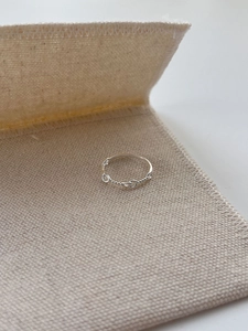 Macro shot of 925 sterling silver twisted rope knot ring on beige textured fabric