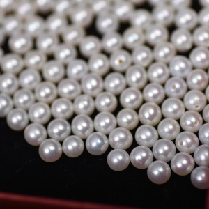 Macro shot of 4mm white natural freshwater pearls with lustrous finish on black velvet