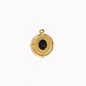 Detail of vintage gold pendant with black oval gemstone and intricate beaded texture