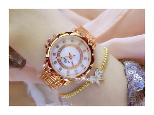 Detail of gold metal watch with crystal bezel and matching bow bracelet on wrist