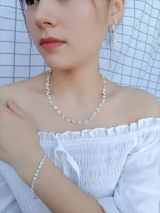 Close-up of elegant silver bridal jewelry set with sparkling rhinestones on a female model