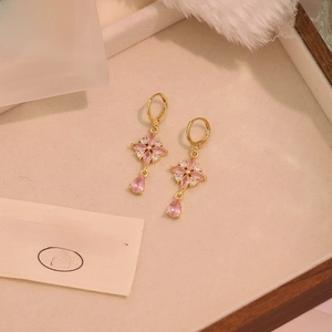 Detail of vintage gold drop earrings with pink crystals on a decorative background