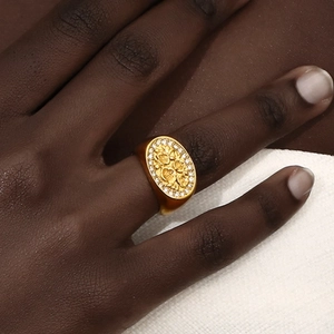 Vintage gold oval signet ring with floral relief and sparkling crystals on model