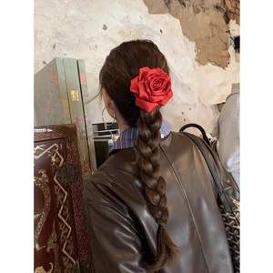 Chouchou fleur en satin rouge de style vintage français porté sur une longue tresse brune