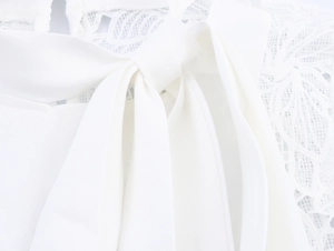 Macro shot of white bow tie and intricate lace pattern on elegant commuter blouse