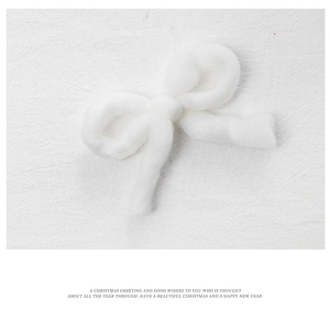 Detail shot of a white plush felt bow ornament with soft texture for Christmas decoration