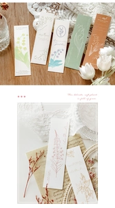 Detail of floral bookmarks with lily of the valley and lily on a rustic wooden desk