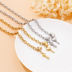 Golden and silver stainless steel chain bracelets with heart and key charms on a white tray