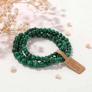 Detail of green malachite gemstone bead bracelet with nature tag on white background