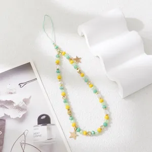 Close-up of beaded phone strap with green and yellow beads and gold star charms