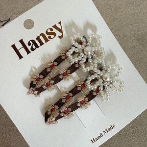 Detailed view of floral embroidery and pearl flowers on brown mesh BB hair clips