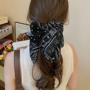 Détail d'un grand bandeau à nœud paisley sur cheveux bouclés avec look rétro