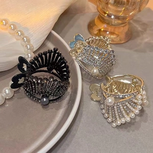 Detailed view of crown hair clips in black, silver, and gold with rhinestones and pearls