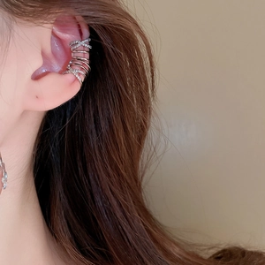 Close-up of a silver multi-layered ear cuff with zircon inlays on a female model's ear