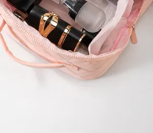 Close-up detail showing the spacious interior of a pink quilted portable cosmetic bag