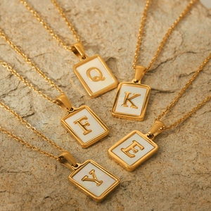 Detail of 18K gold plated stainless steel rectangle pendants with white shell letter inlays