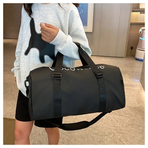 Model showing black fitness bag with white lettering and adjustable shoulder strap