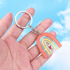 Sweet rainbow keychain with heart detail and silver ring holder against a blue sky background