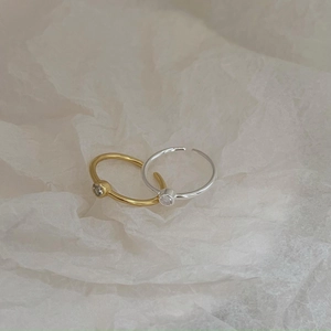 Macro shot of gold and silver minimalist rings with tiny zircons on gray tissue paper