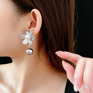 Gros plan sur boucle d'oreille fleur argentée avec perle et bille métallique sur modèle