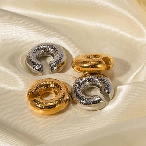 Textured C-shaped gold and silver stainless steel ear cuffs on premium silk background