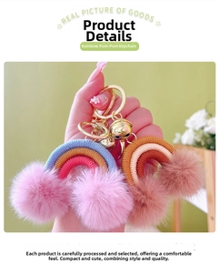 Detail of colorful rainbow pom pom keychain with gold ring and bell on a green background