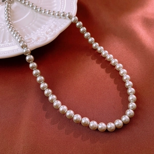 Elegant white pearl necklace displayed on dark red silk fabric with vintage aesthetic