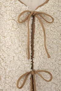 Gros plan détaillé du gilet en polaire beige avec fermetures à nœuds marron chic